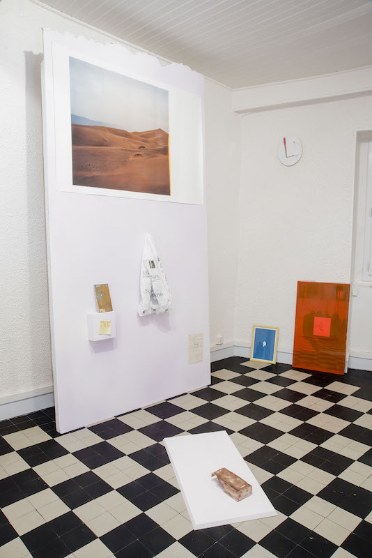 Cimaise de haut en bas : Sans titre (Sahara II), Léa Mercier, 2015, 75 x 110 cm, photographie argentique, tirage sur papier mat Secret Power, Simon Denny, 2015, dimensions variables, sac plastique 50 shades, extrait d’une série de 50 peintures, Florent Frizet & Caroline Saves, 2015, 16 x 9 cm, bois, acrylique, vernis, aquarelle, paillettes Sans titre (regarder de face), Inconnu, 2015, 7.5 x 7.5 cm, écriture sur post-it Emprunteuse éclaireuse Caroline, Bruno Rey, 2016, 21 x 14.85 cm, dessin sur papier  Au sol premier plan : Don ́t make a wall make a brick, extrait d’une série de 10 modules, Lisa Algayer, 2015-2016, 3.5 x 17 x 7.5 cm, céramique et faïence émaillée  Mur du fond : Victor, Inconnu, 2018, 26 x 21 cm, bois, peinture Pli #000, Marie Clerel, 2015, 27 x 19 cm, cyanotype sur papier aquarelle Sans Titre, Florent Frizet, 2015, 31 x 44 x 4.5 cm, cloche en plexiglass, peinture à la bombe, acrylique Photo © Diego Guglieri Don Vito