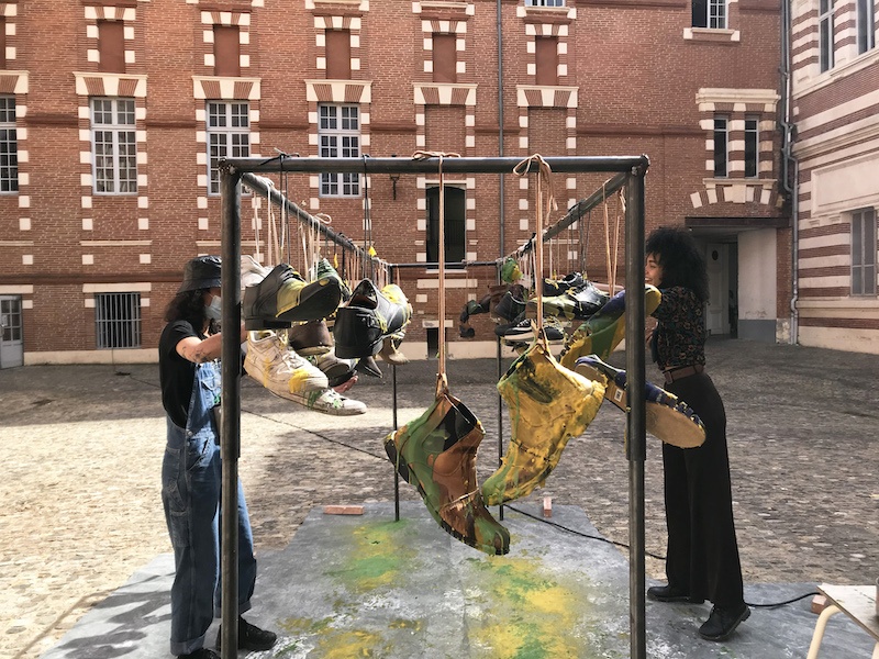 Carla Lloret Palmero, Stand de cirage de pompes, 2021. Cire, paires de chaussures. 350x70x170cm Photographie lors de la performance.